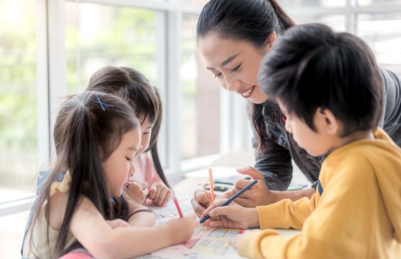女性と子供達が絵を描いている写真
